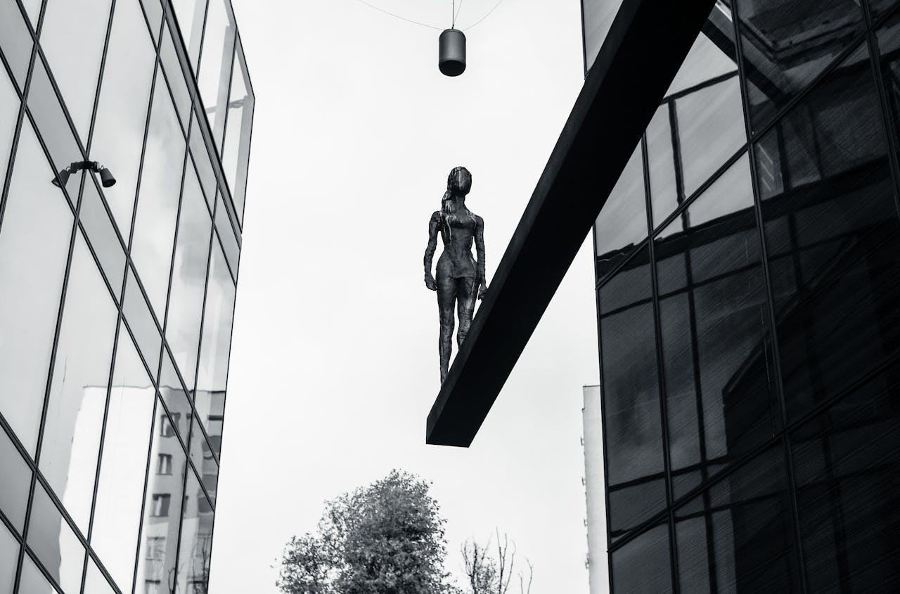 gallery-2 A striking bronze sculpture elevated between modern buildings in an urban cityscape.